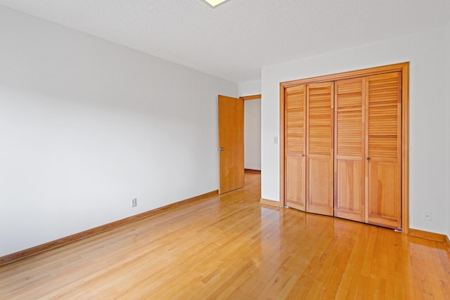 unfurnished bedroom with a textured ceiling, hardwood / wood-style flooring, and a closet