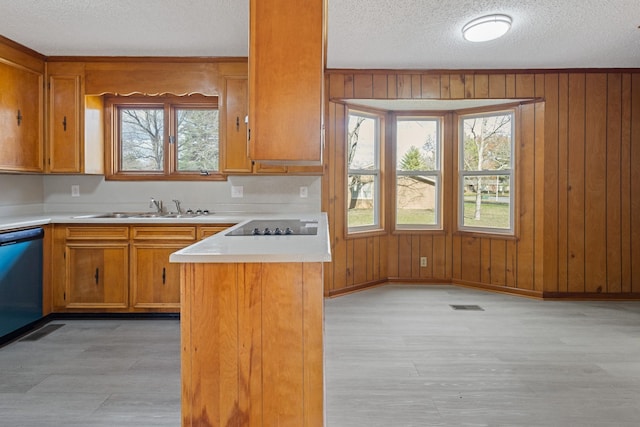 kitchen with kitchen peninsula, a textured ceiling, black appliances, sink, and wood walls