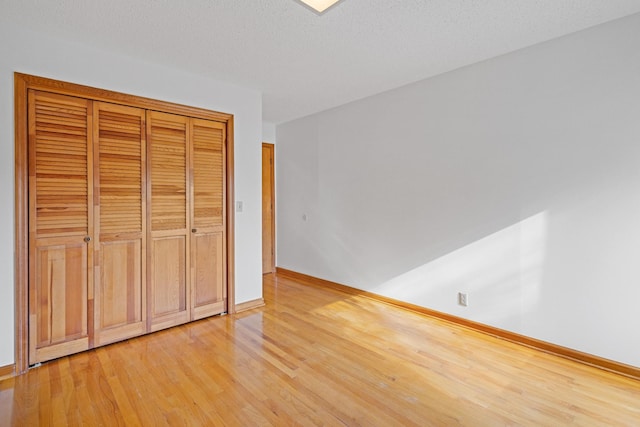 unfurnished bedroom featuring a closet, light hardwood / wood-style flooring, and a textured ceiling