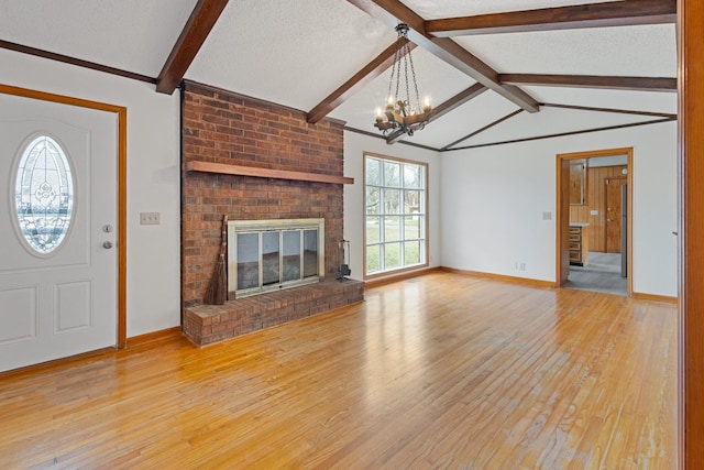 unfurnished living room with lofted ceiling with beams, a chandelier, a textured ceiling, a fireplace, and light wood-type flooring