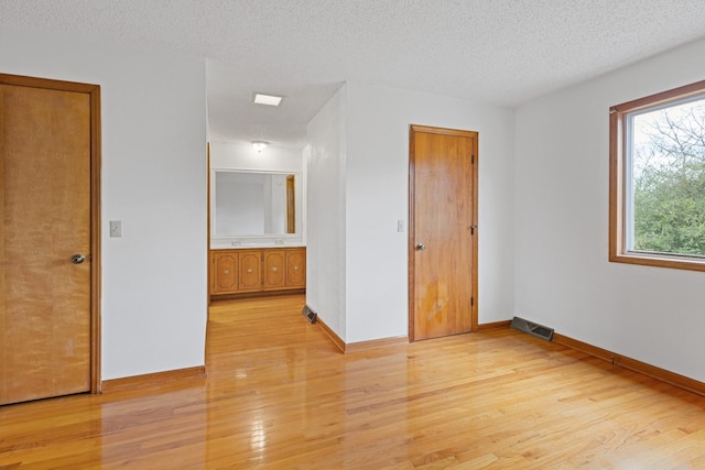 spare room with light hardwood / wood-style floors and a textured ceiling