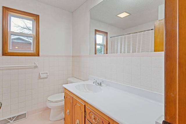 bathroom with walk in shower, a textured ceiling, vanity, tile walls, and toilet