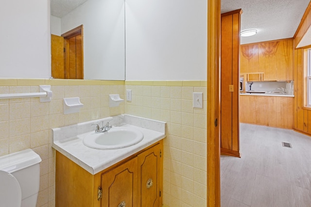 bathroom with tile walls, vanity, and a textured ceiling