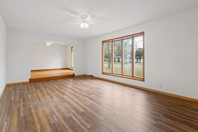 empty room with ceiling fan, wood-type flooring, and a textured ceiling