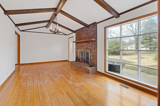 unfurnished living room featuring vaulted ceiling with beams, an inviting chandelier, light hardwood / wood-style floors, and a brick fireplace