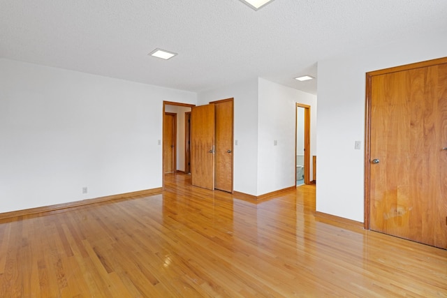 spare room with light wood-type flooring and a textured ceiling