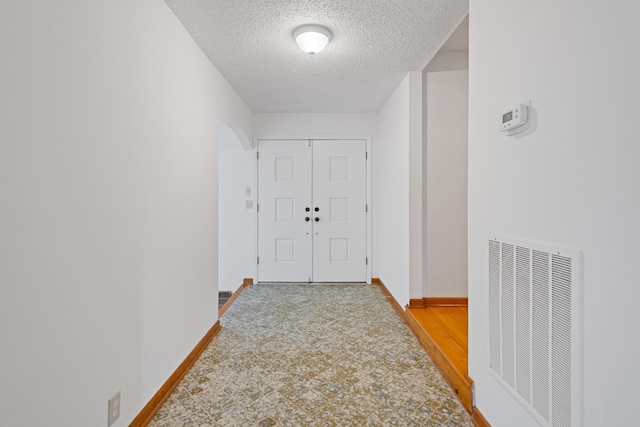 corridor featuring a textured ceiling and hardwood / wood-style flooring