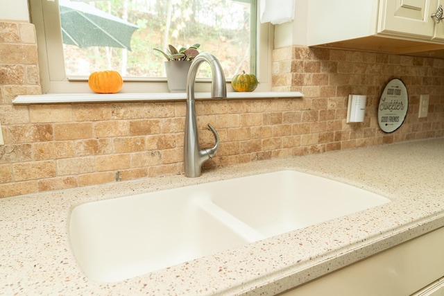 interior details with backsplash, light stone counters, and sink