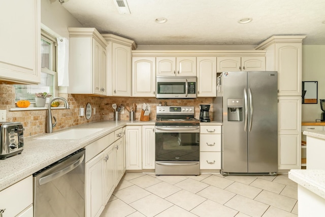 kitchen with decorative backsplash, sink, stainless steel appliances, and cream cabinets