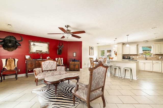 tiled living room featuring ceiling fan, sink, and a textured ceiling