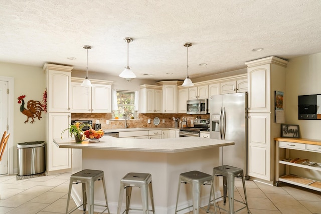 kitchen featuring appliances with stainless steel finishes, hanging light fixtures, a kitchen breakfast bar, and sink