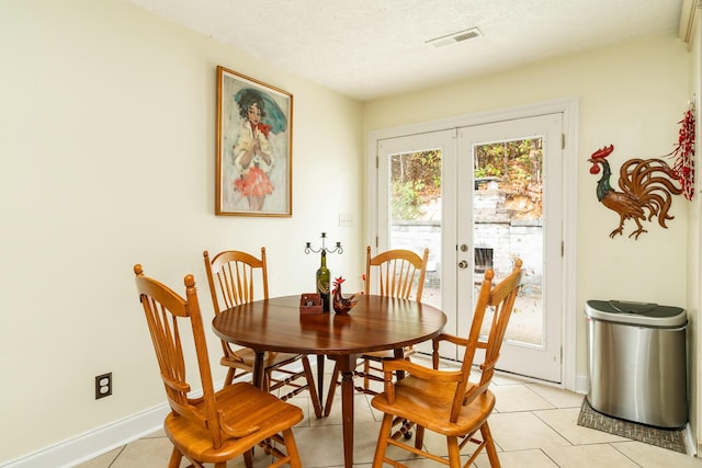 dining room with french doors, a textured ceiling, and light tile patterned floors