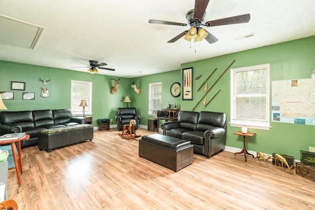 living room with plenty of natural light, ceiling fan, a textured ceiling, and light hardwood / wood-style flooring