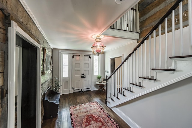 entrance foyer with a chandelier, dark hardwood / wood-style flooring, and crown molding