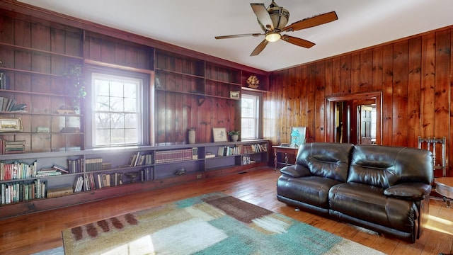 living room with wooden walls, a healthy amount of sunlight, and wood-type flooring