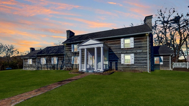 back house at dusk with a lawn