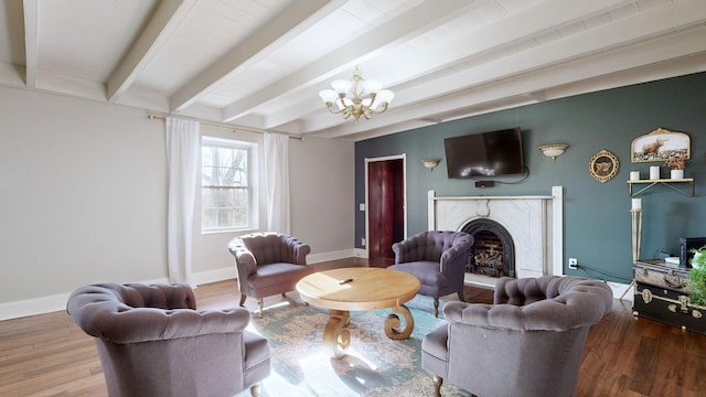 living room with hardwood / wood-style flooring, a notable chandelier, beam ceiling, and a high end fireplace