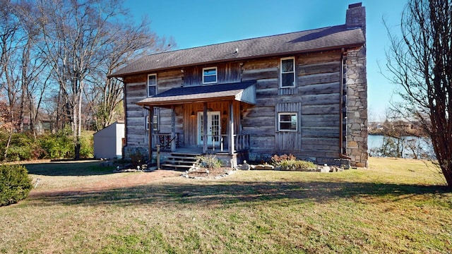 view of front facade featuring covered porch, an outbuilding, and a front lawn