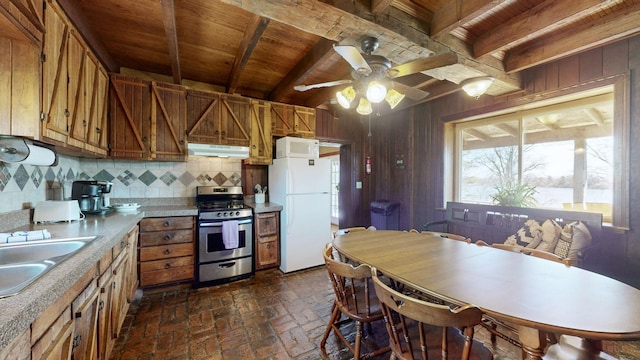 kitchen featuring decorative backsplash, white appliances, ceiling fan, sink, and wood walls