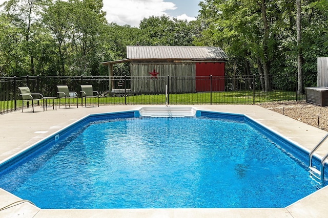 view of pool featuring an outbuilding, a patio area, and a lawn