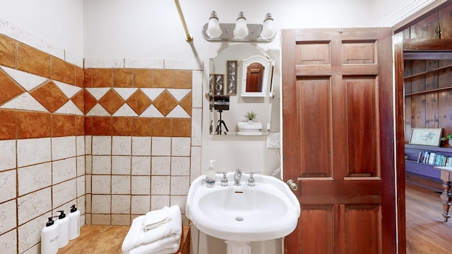 bathroom with hardwood / wood-style flooring, sink, and tile walls