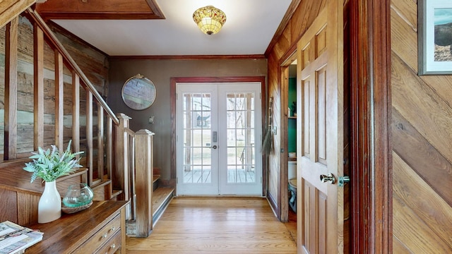 doorway to outside with wood walls, french doors, ornamental molding, and light wood-type flooring