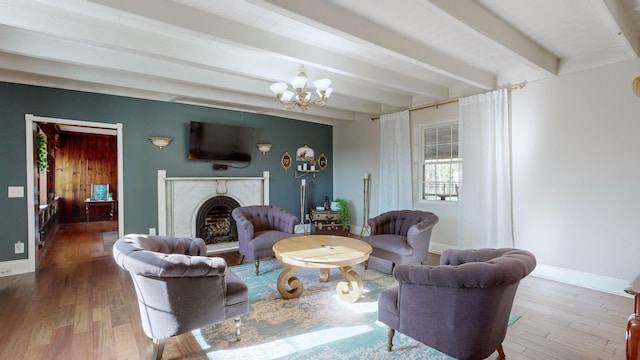 living room with a fireplace, beam ceiling, hardwood / wood-style flooring, and an inviting chandelier