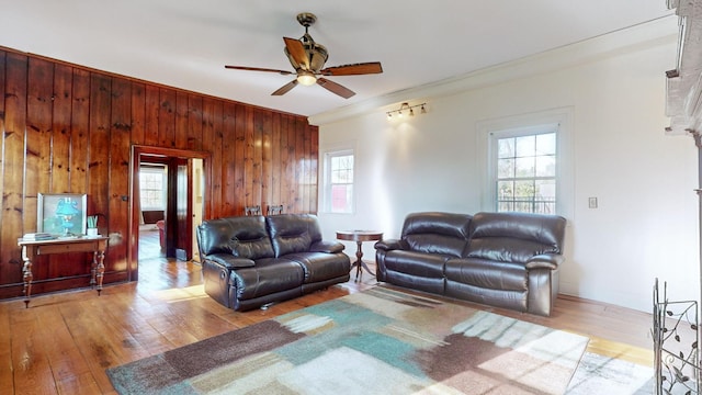 living room with wood-type flooring, ceiling fan, a wealth of natural light, and wood walls