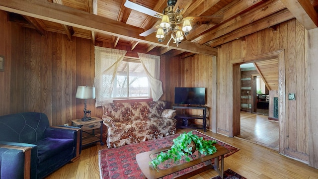 living room with beam ceiling, hardwood / wood-style flooring, ceiling fan, and wooden walls