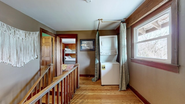 hall featuring stacked washing maching and dryer and light hardwood / wood-style floors