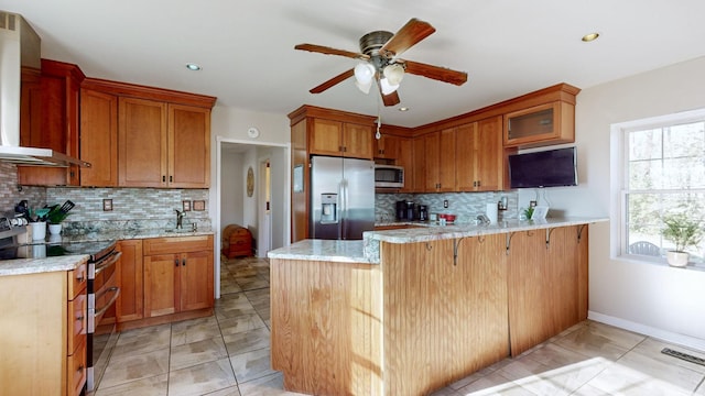 kitchen with sink, wall chimney range hood, tasteful backsplash, kitchen peninsula, and appliances with stainless steel finishes