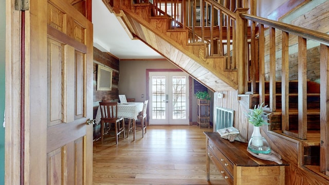 interior space featuring french doors, light wood-type flooring, and wood walls