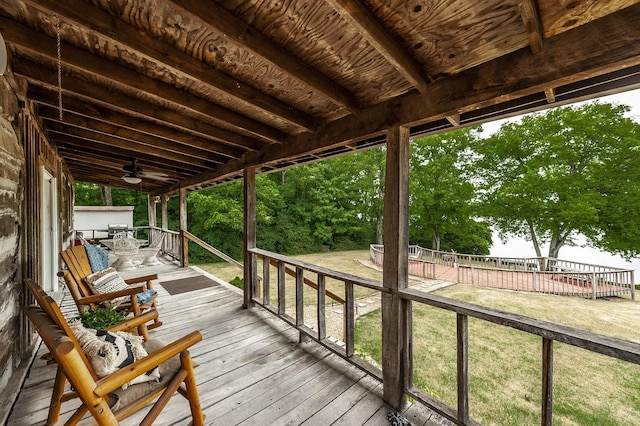 wooden terrace featuring ceiling fan and a lawn