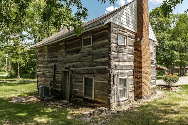 view of side of home with a lawn and cooling unit