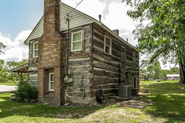 view of side of property with a lawn and central AC