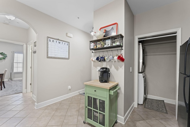 hall featuring stacked washer / drying machine and light tile patterned flooring