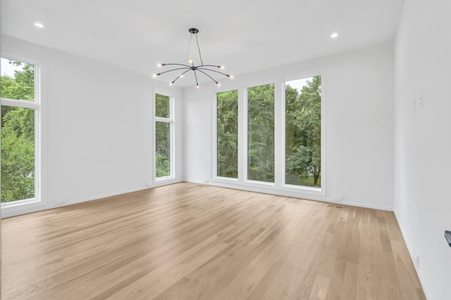 empty room with light wood-type flooring, plenty of natural light, and a notable chandelier