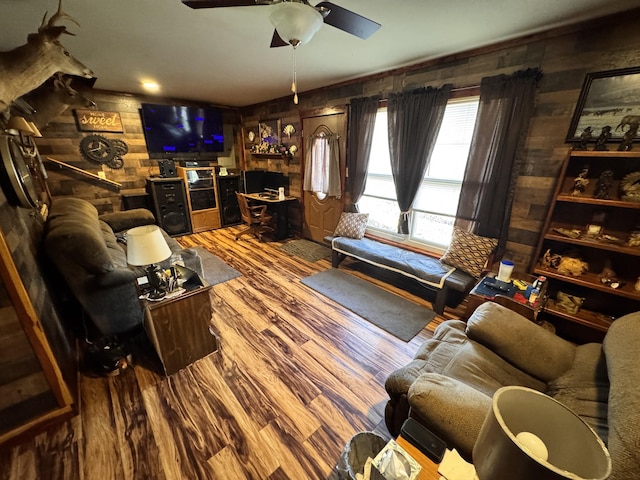 living room featuring hardwood / wood-style flooring, ceiling fan, and wooden walls