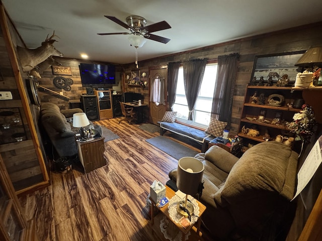 living room with wood-type flooring, ceiling fan, and wood walls