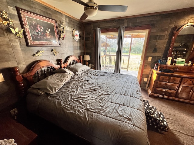 carpeted bedroom featuring access to exterior, ceiling fan, and wooden walls