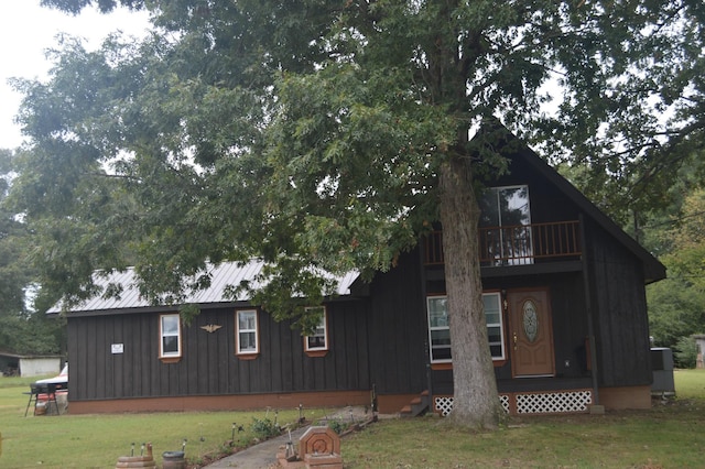 rear view of house featuring a lawn and a balcony