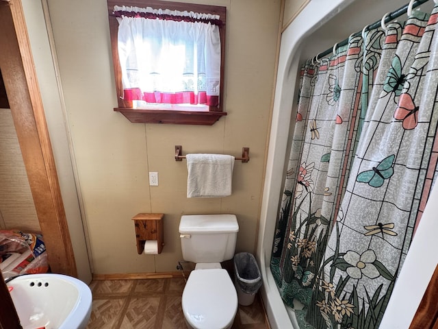 bathroom with parquet flooring, a shower with curtain, and toilet