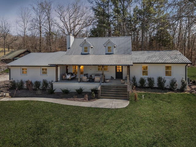 view of front of house featuring a patio area, a chimney, metal roof, and a front yard