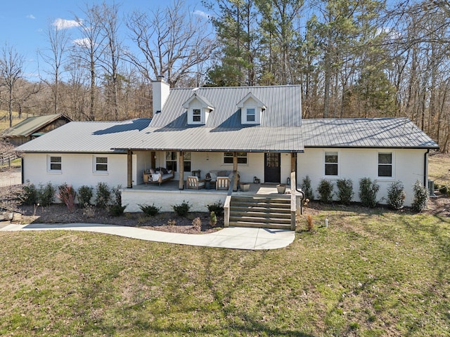 view of front of house featuring brick siding, metal roof, a chimney, and a front lawn