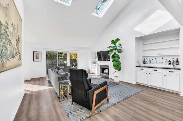 living room featuring bar area, high vaulted ceiling, and light hardwood / wood-style flooring