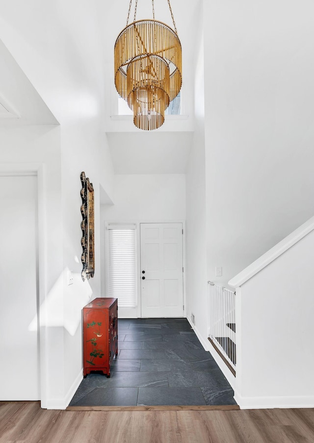 entryway with a towering ceiling, dark hardwood / wood-style flooring, and an inviting chandelier