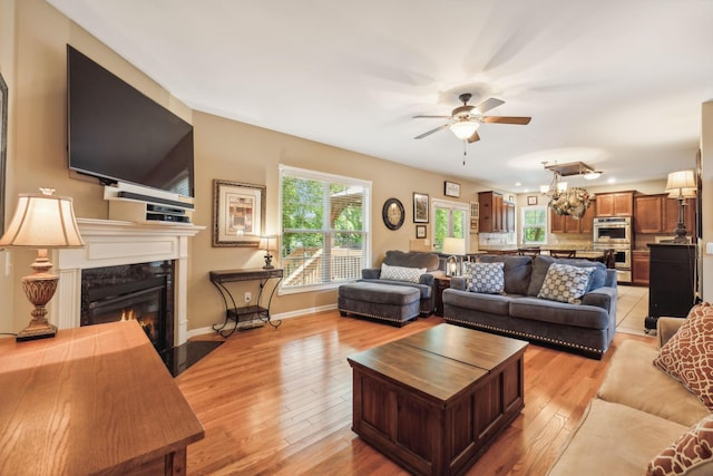 living room featuring ceiling fan, light hardwood / wood-style floors, and a fireplace