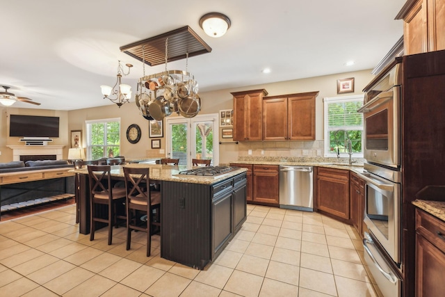 kitchen with sink, light tile patterned floors, a kitchen bar, a kitchen island, and appliances with stainless steel finishes