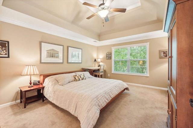 bedroom featuring ceiling fan, light colored carpet, ornamental molding, and a tray ceiling