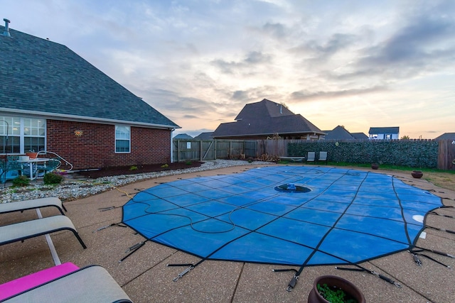 pool at dusk with a patio area